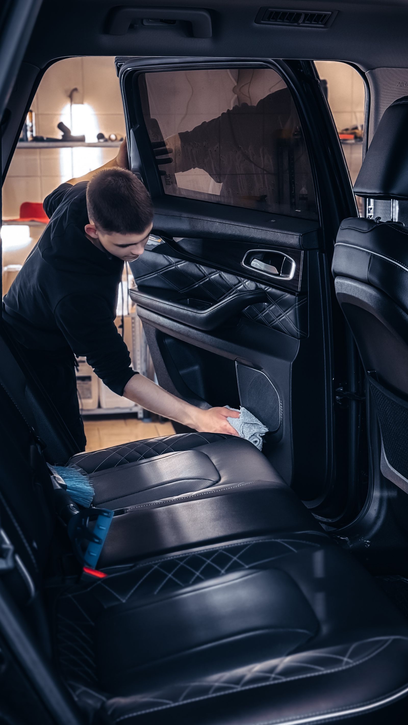 Detailer cleaning leather upholstery and the inside of a car door