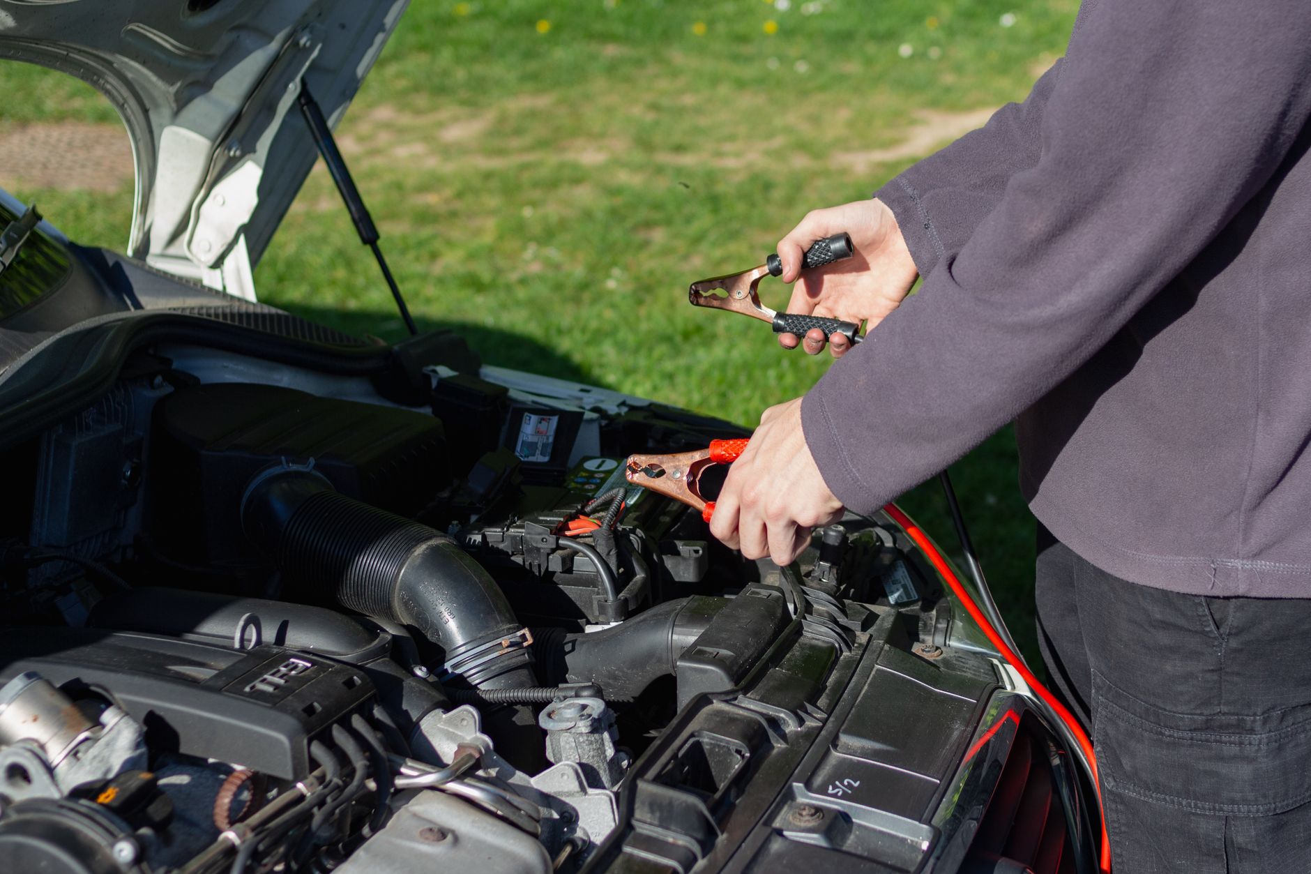 Mechanic using jumper cables on a car battery