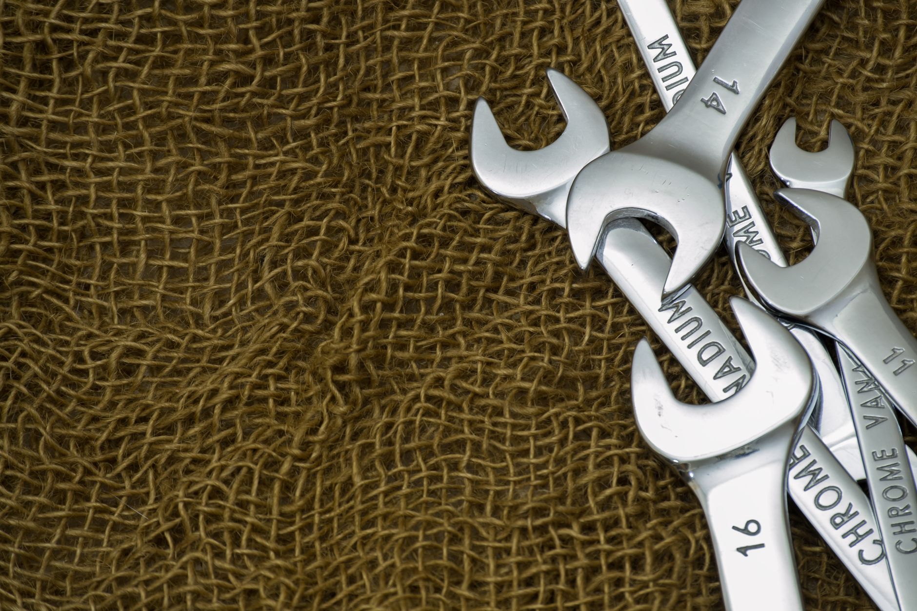 Silver wrenches arranged on textured burlap fabric