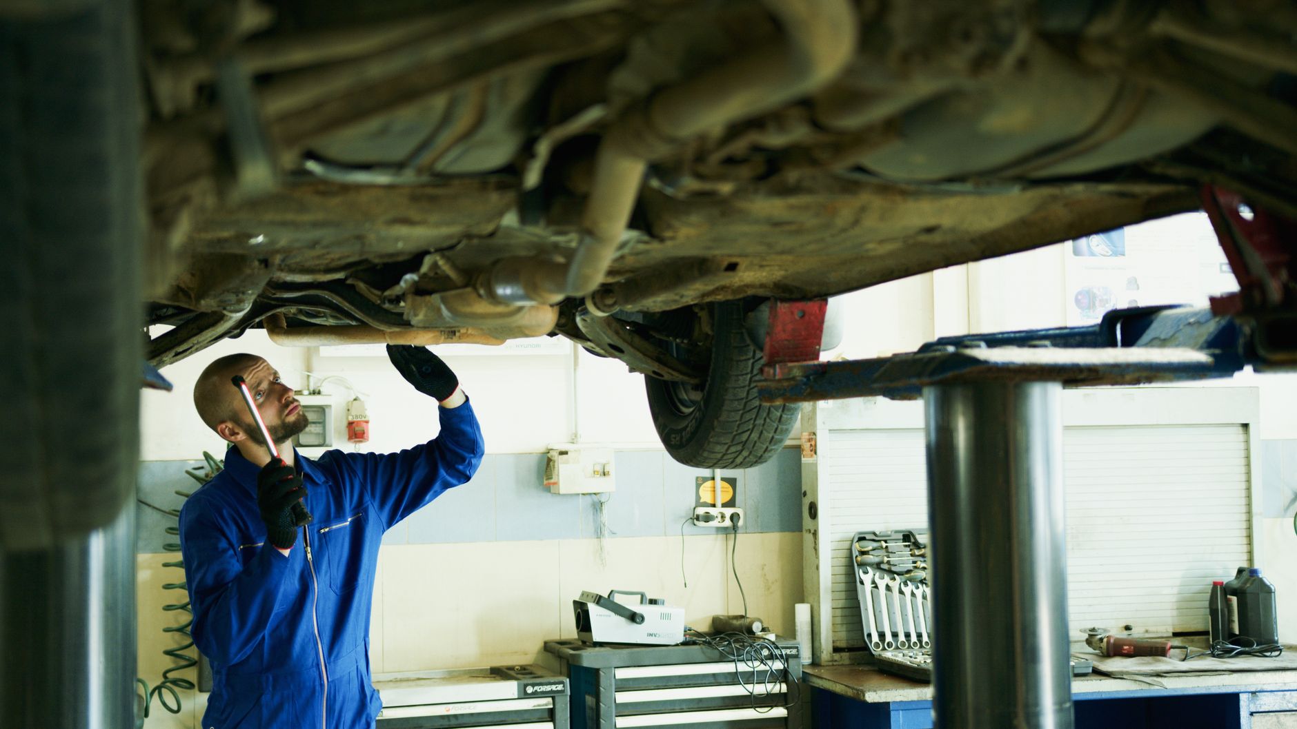 Mechanic inspecting the underside of a car on a lift