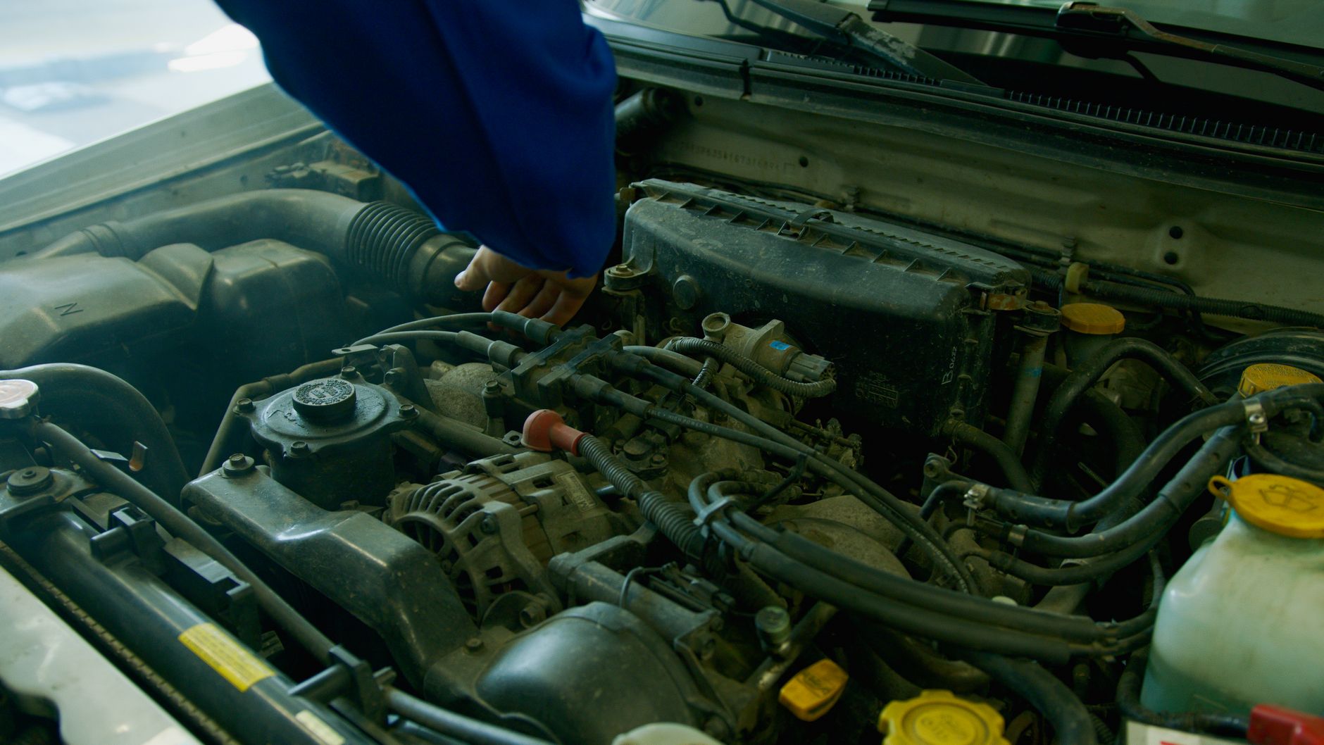 A mechanic working under a car on an oil change