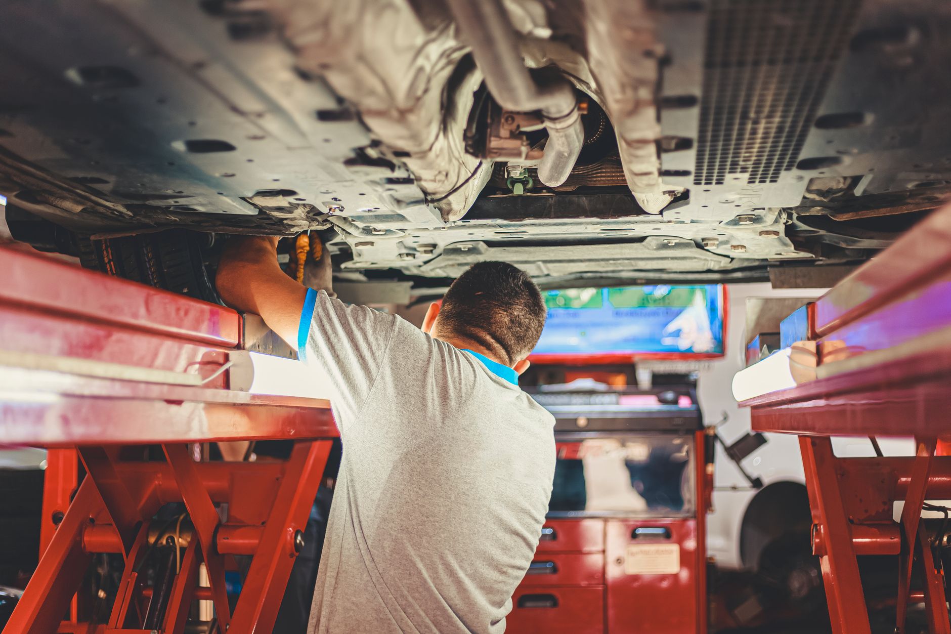 Photo of a mechanic working under a lifted car in a repair bay