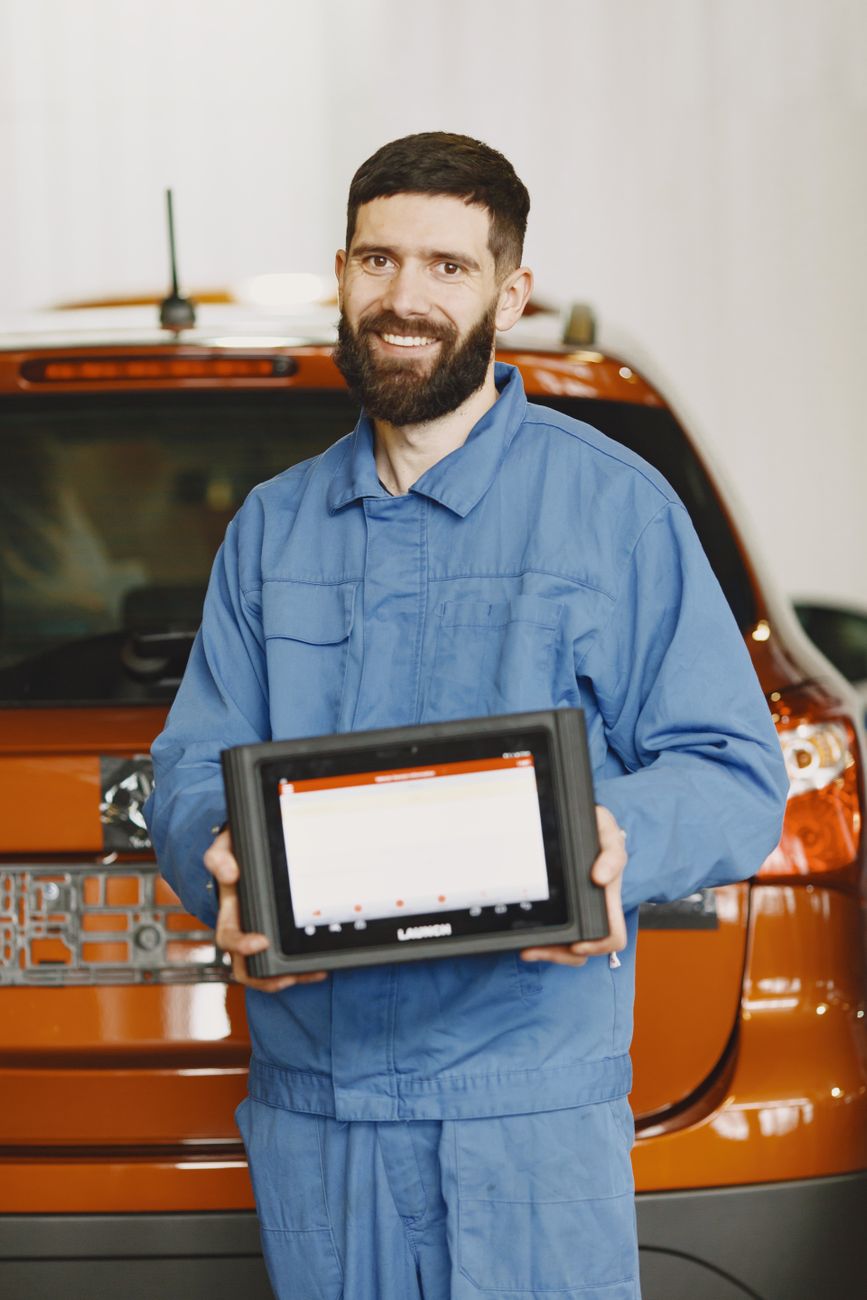 Portrait of a mechanic in blue coveralls holding a diagnostic tablet