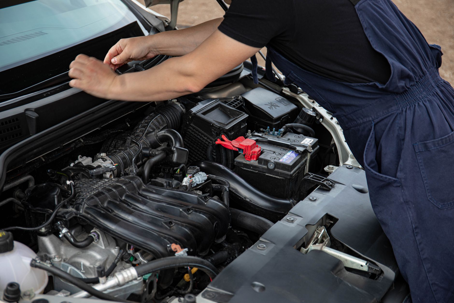 Photo of a mechanic maintaining a car battery and engine