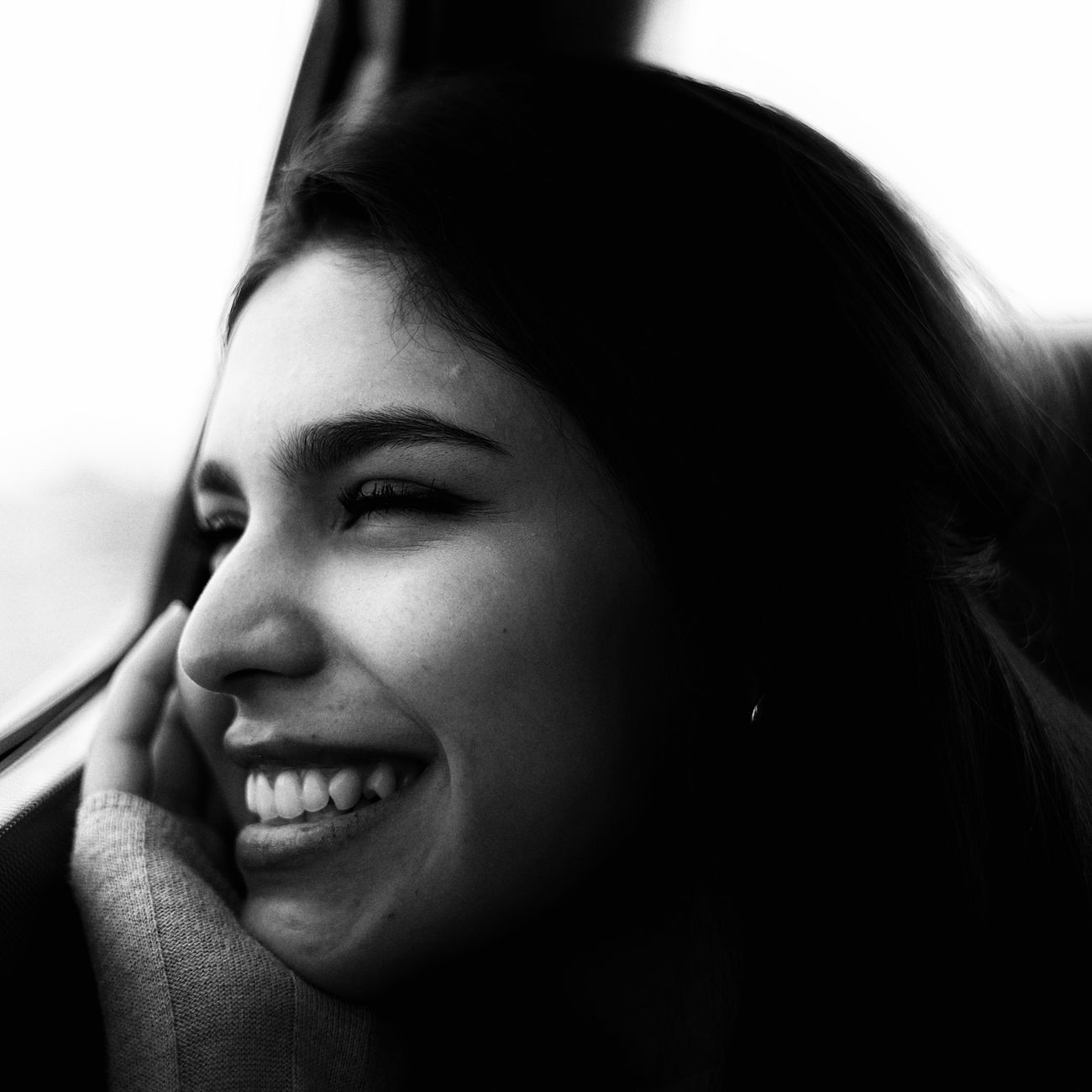 Black and white portrait of a cheerful woman by a window