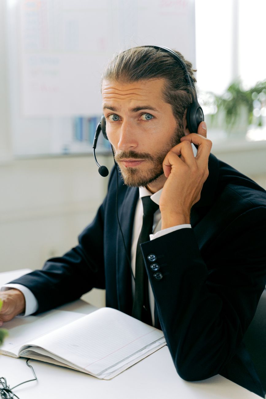 A service advisor in a business suit wearing a headset at the desk