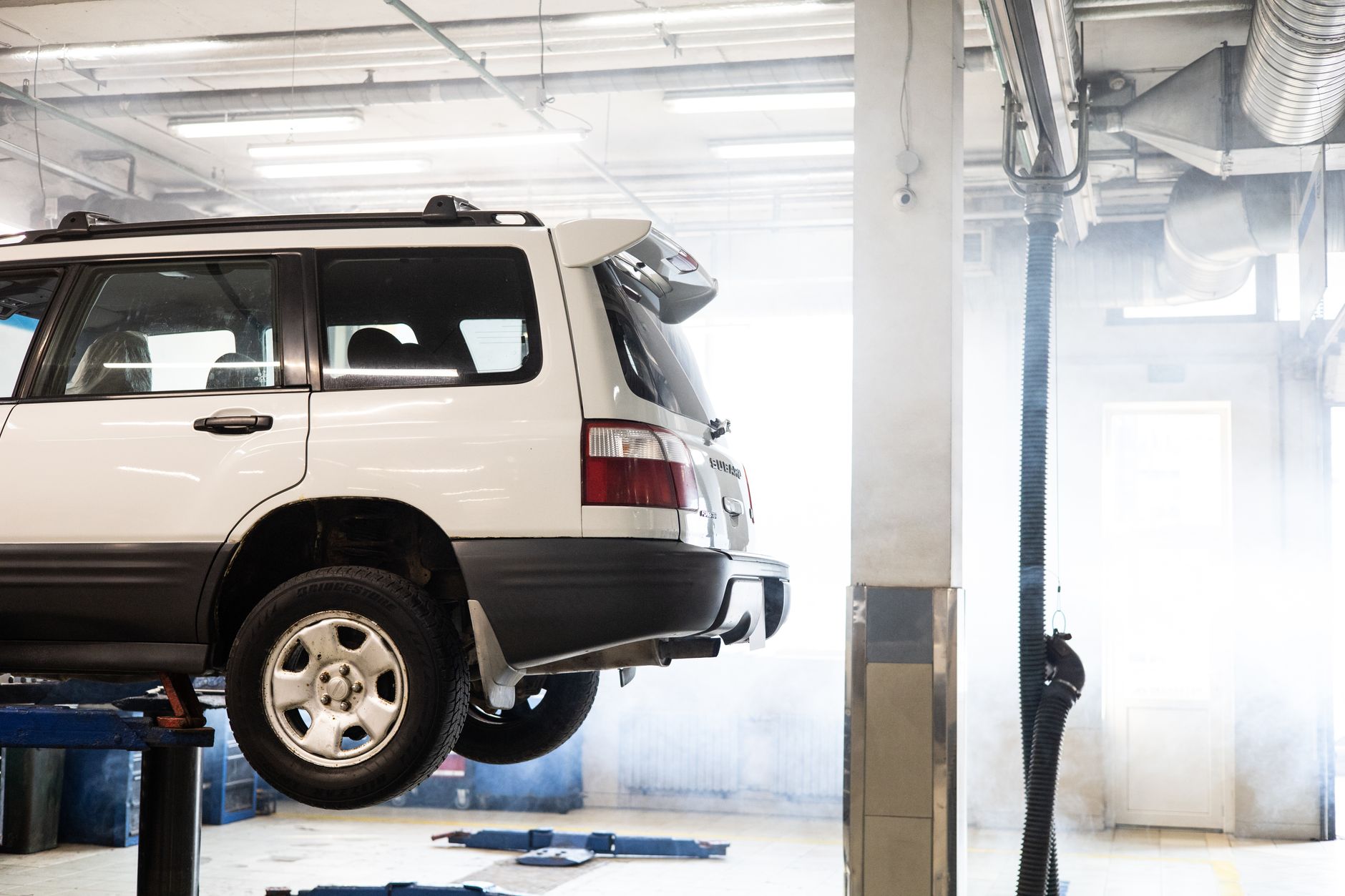 A white SUV raised on a lift in the workshop