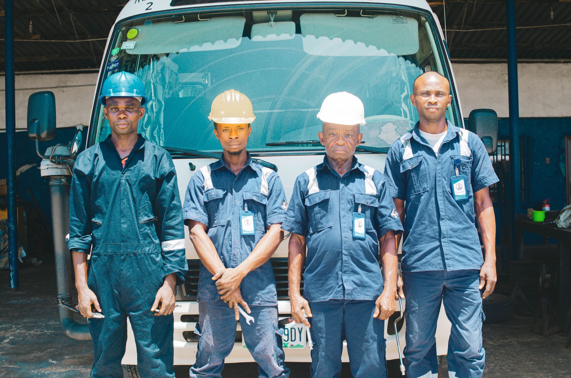 A crew of mechanics in uniforms and hard hats standing in the garage
