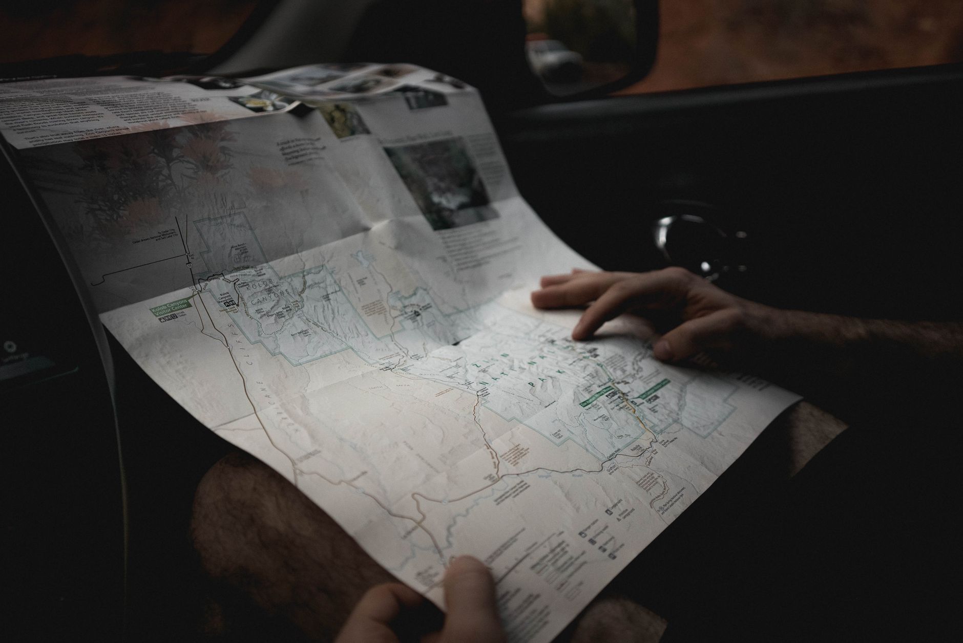 A man in a car reading a paper road map