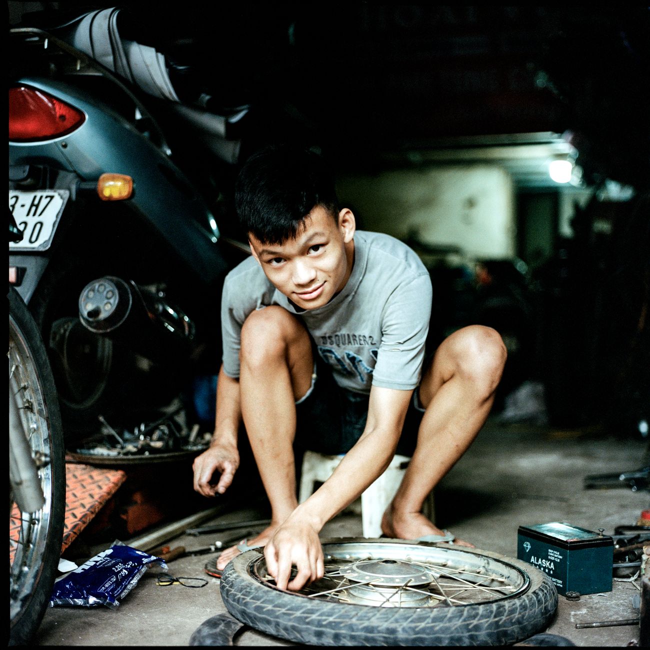 A mechanic working on a wheel inside a workshop