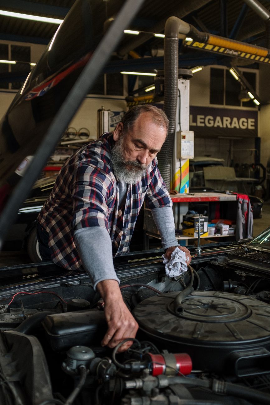 A bearded mechanic repairing a car engine in a workshop