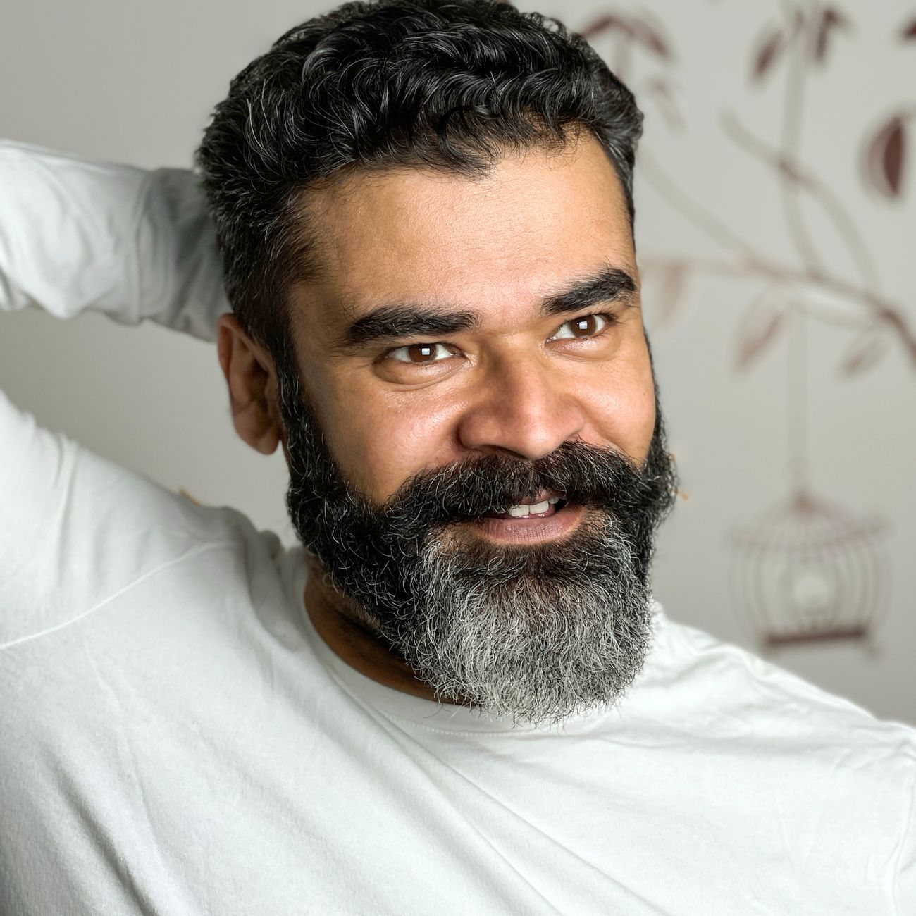 A smiling bearded man in a white shirt