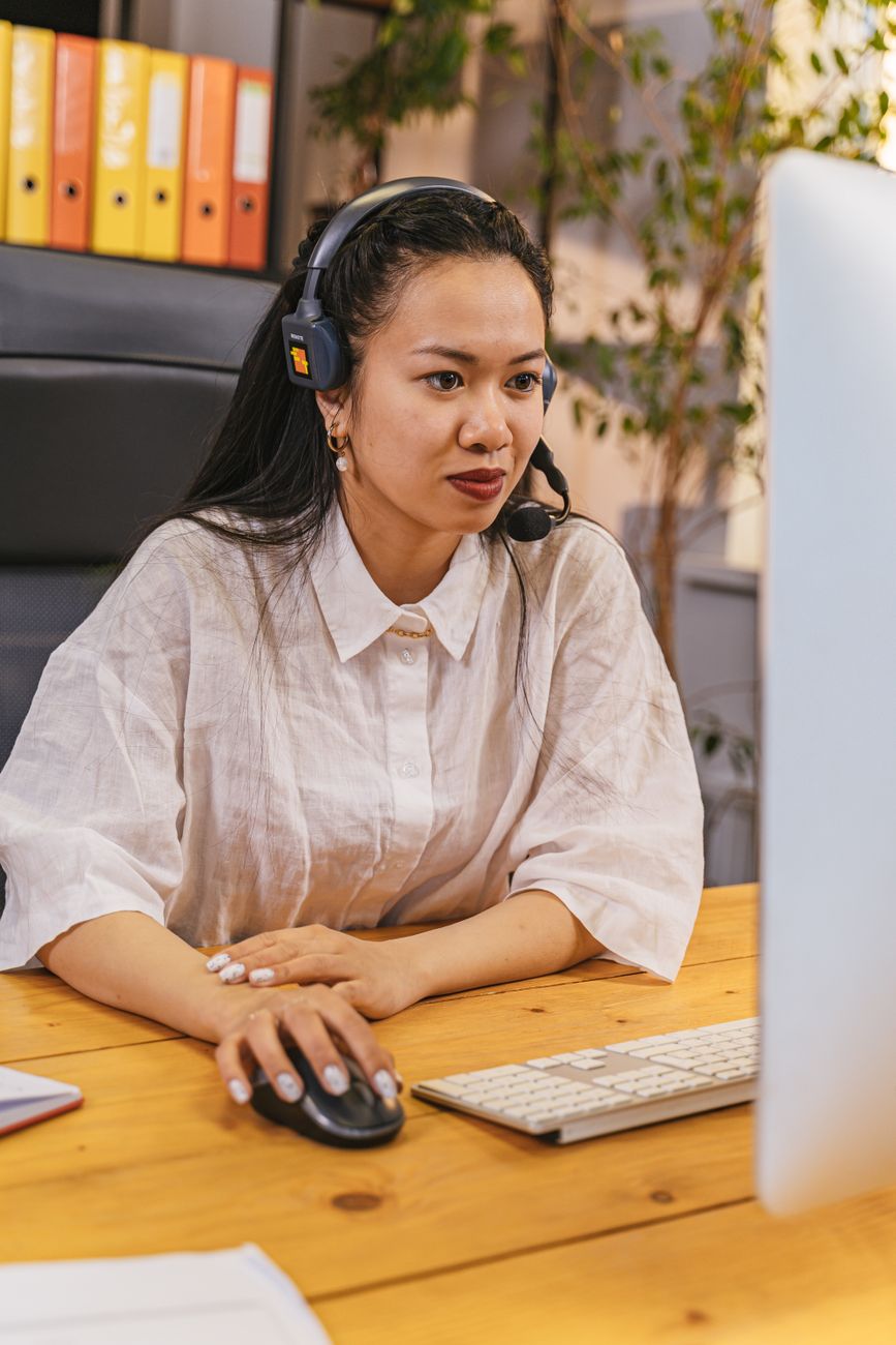 A service advisor using a computer and headset at a desk