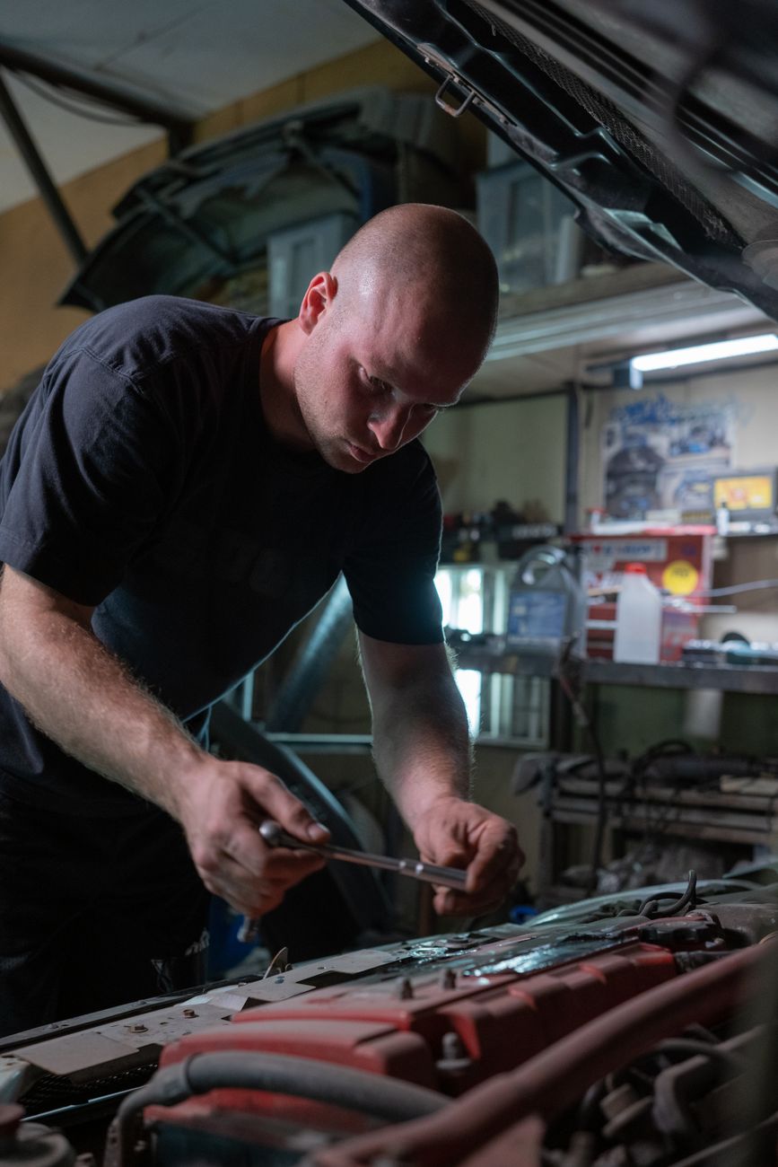 A mechanic working inside a garage fixing a car engine