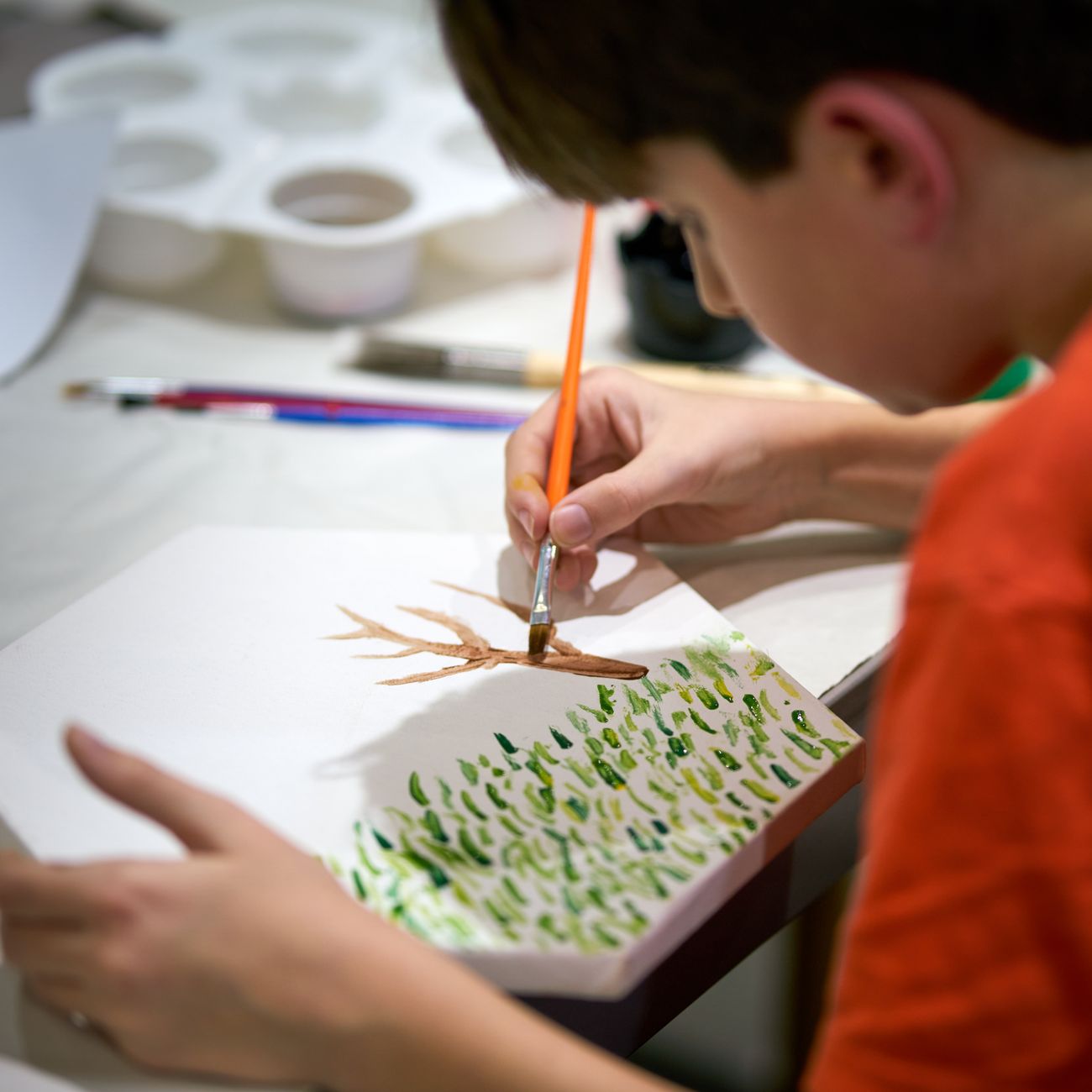 Child hands painting at a table of art materials