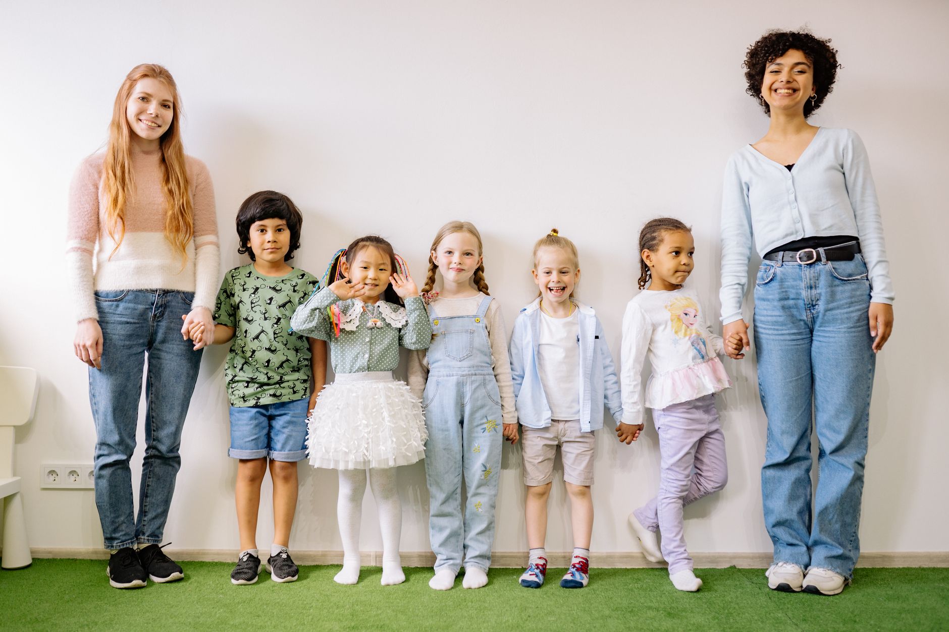 A group of children and their teachers posing together in a bright classroom