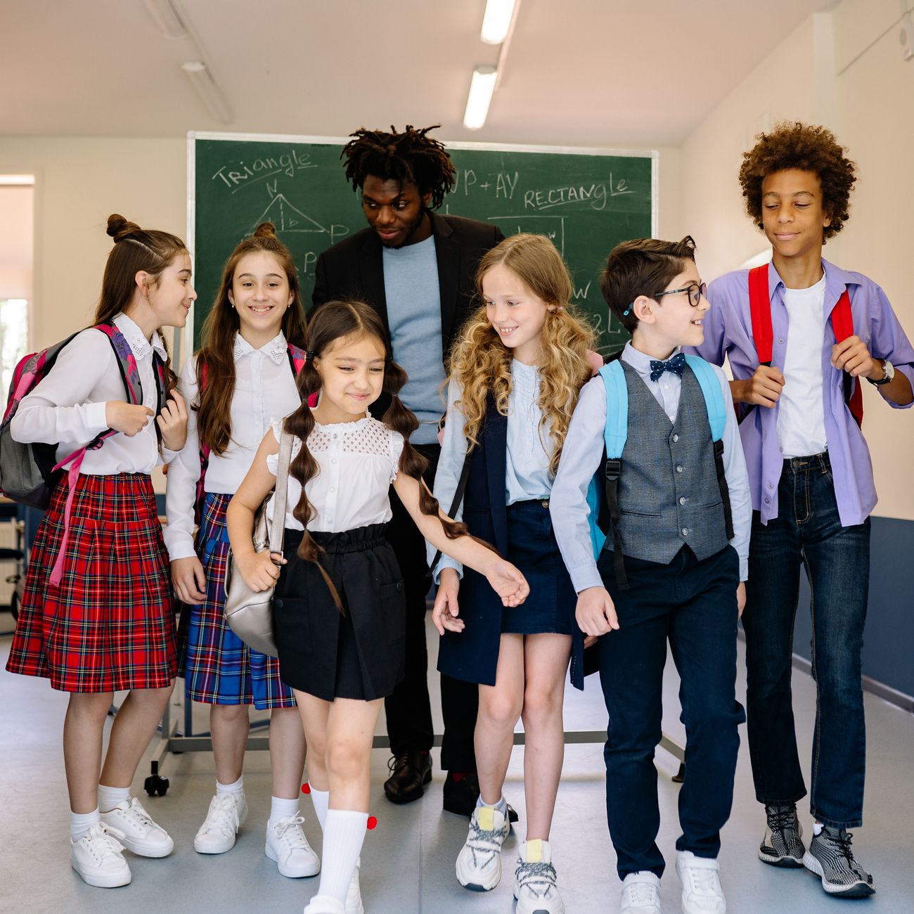A group of schoolchildren with their teacher walking inside a classroom