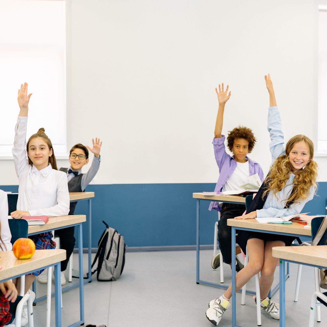 Students raising their hands in a bright classroom