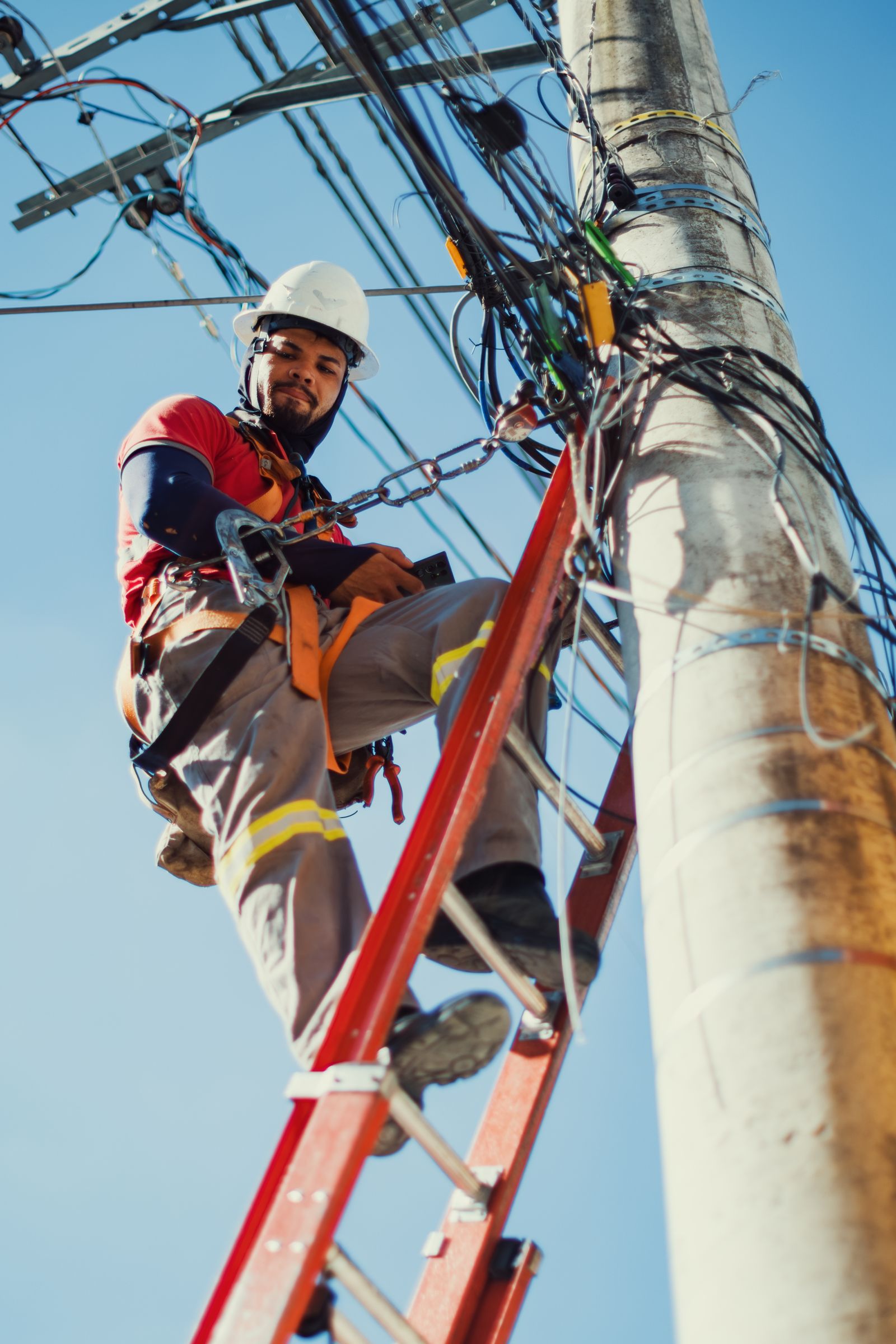 Licensed electrician servicing overhead power lines from a ladder